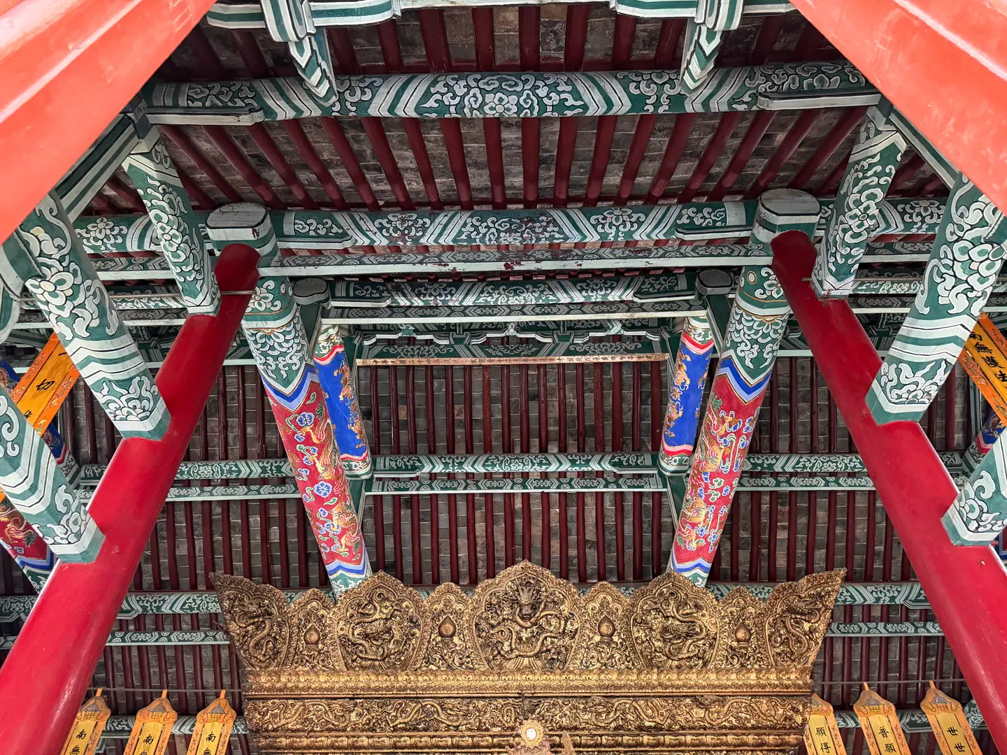 Vigas y ménsulas pintadas en rojo, verde y oro bajo el alero de un salón del templo del Caballo Blanco