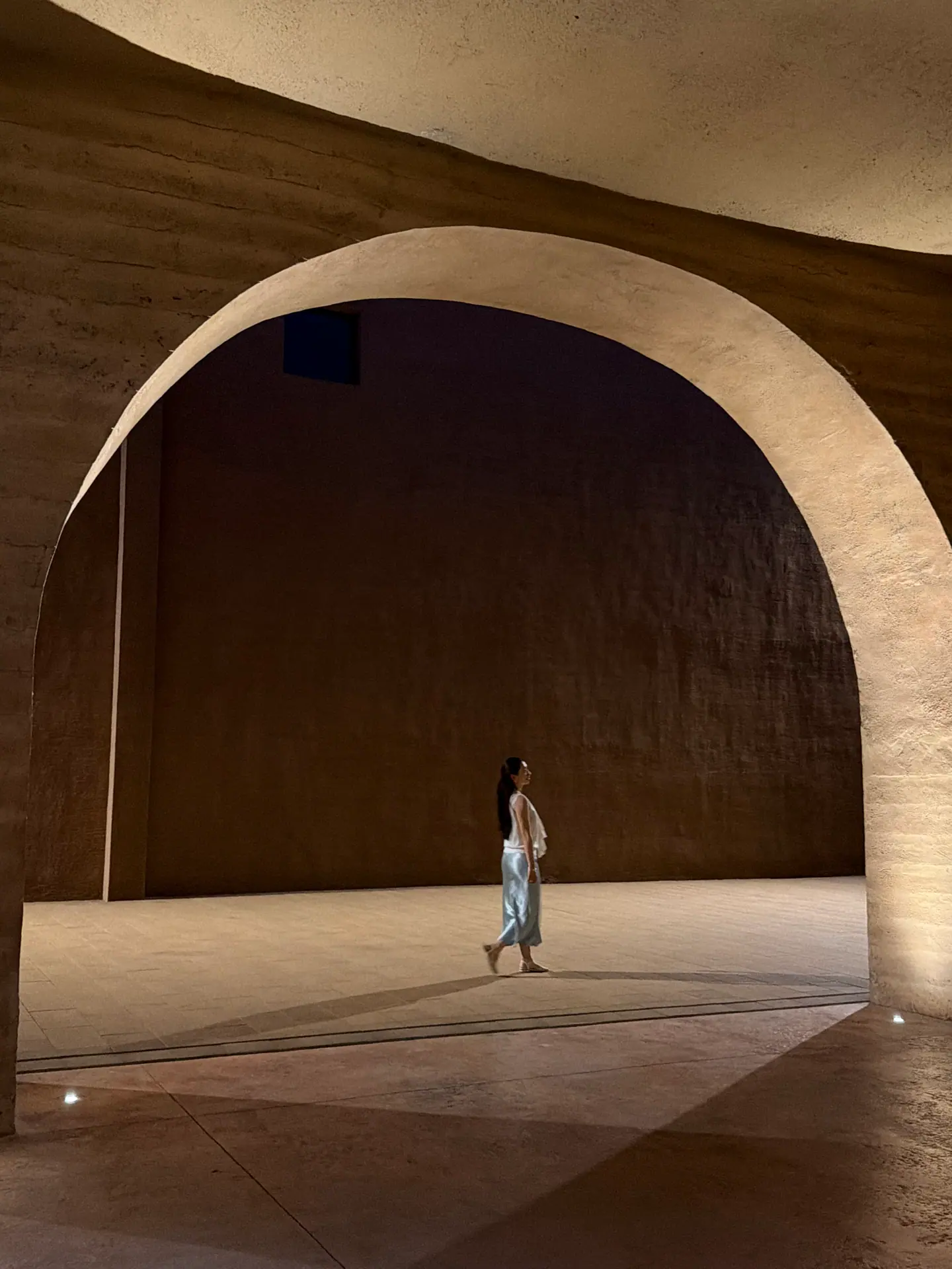 Visitante bajo un arco monumental en una gran sala de tierra de Only Henan