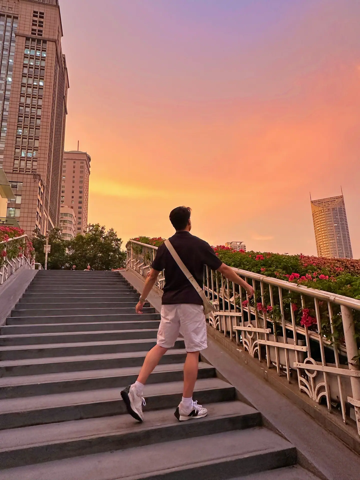 Viajero subiendo una escalinata en Cantón bajo un cielo rosado al atardecer