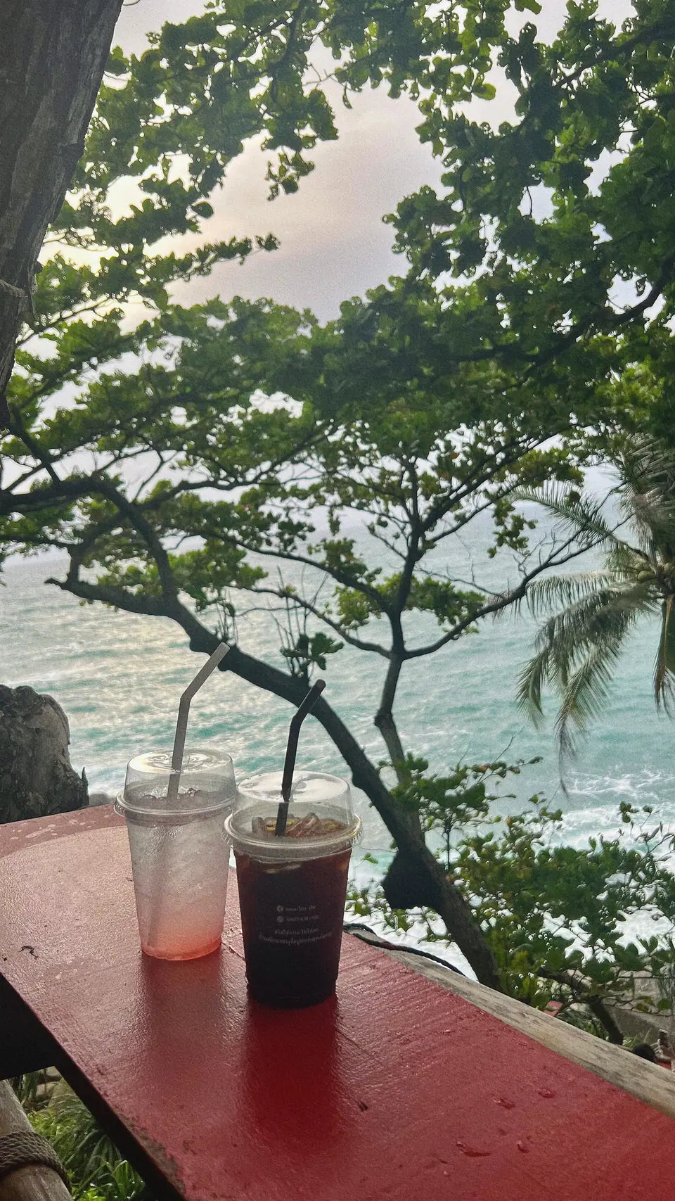 Mesa con bebidas frente al mar entre árboles en un café de Phuket