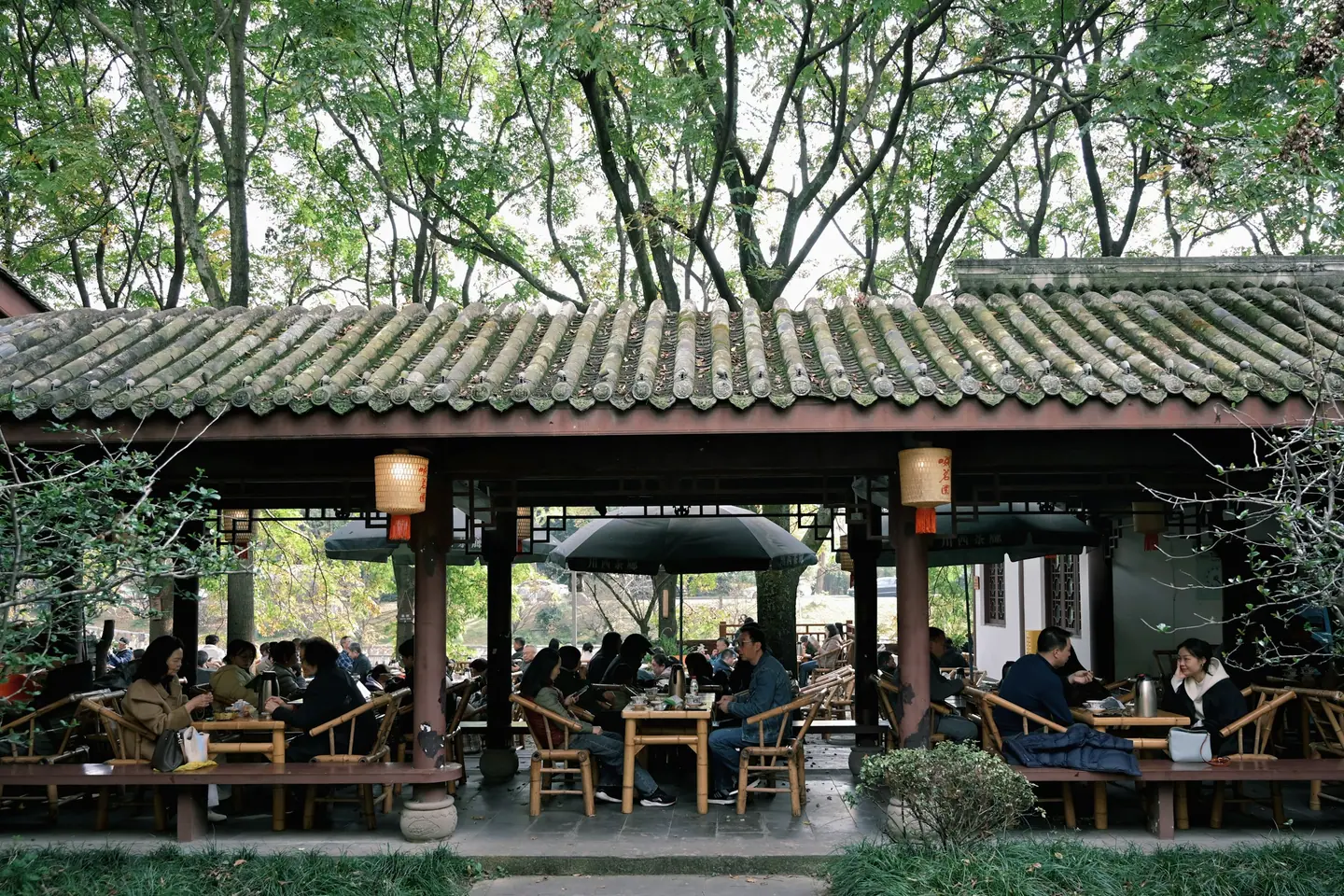 Gente tomando té bajo un tejado tradicional en un parque de Chengdu