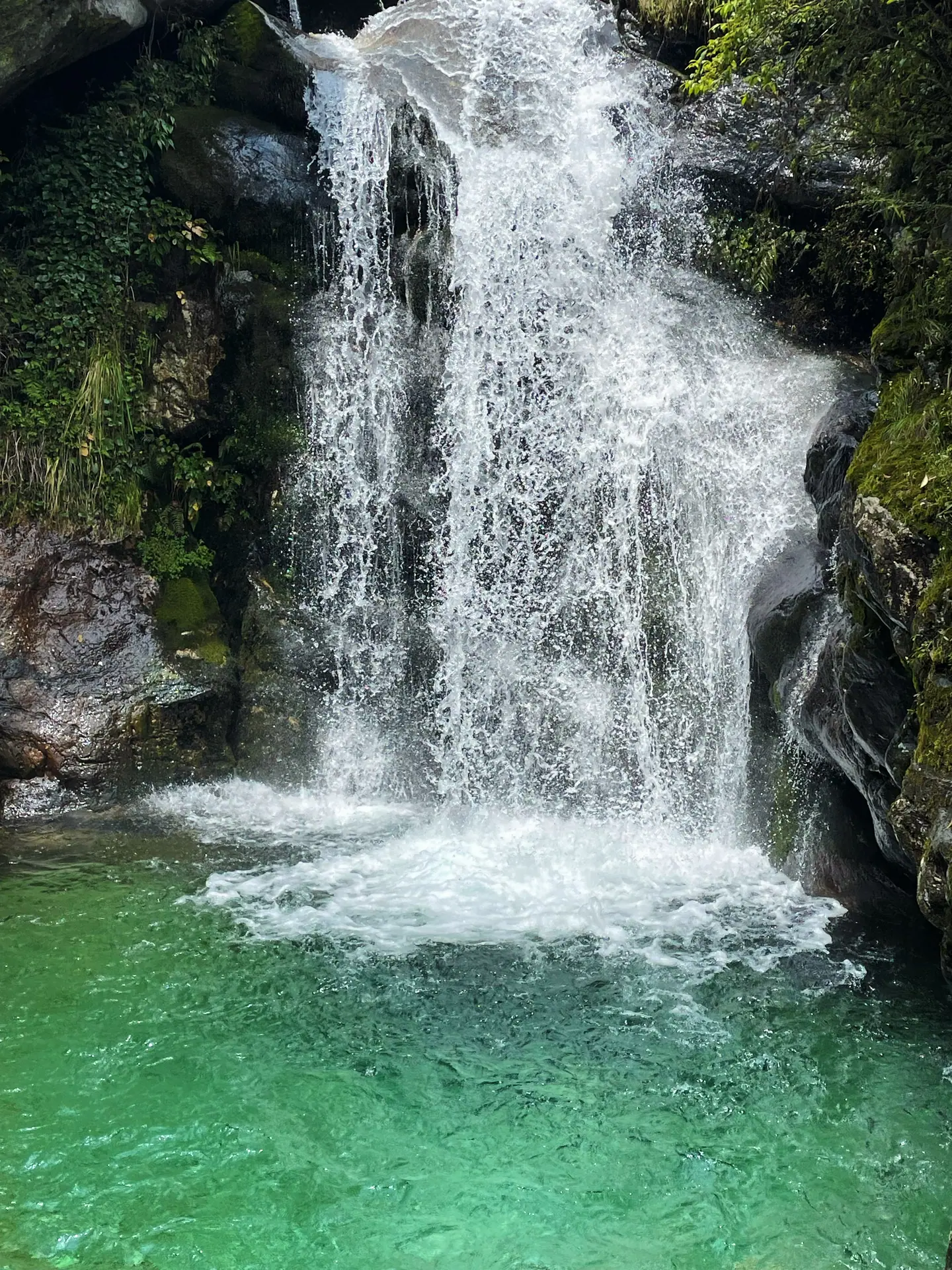 Cascada que cae en una poza de aguas turquesas en la montaña Cangshan, Dali