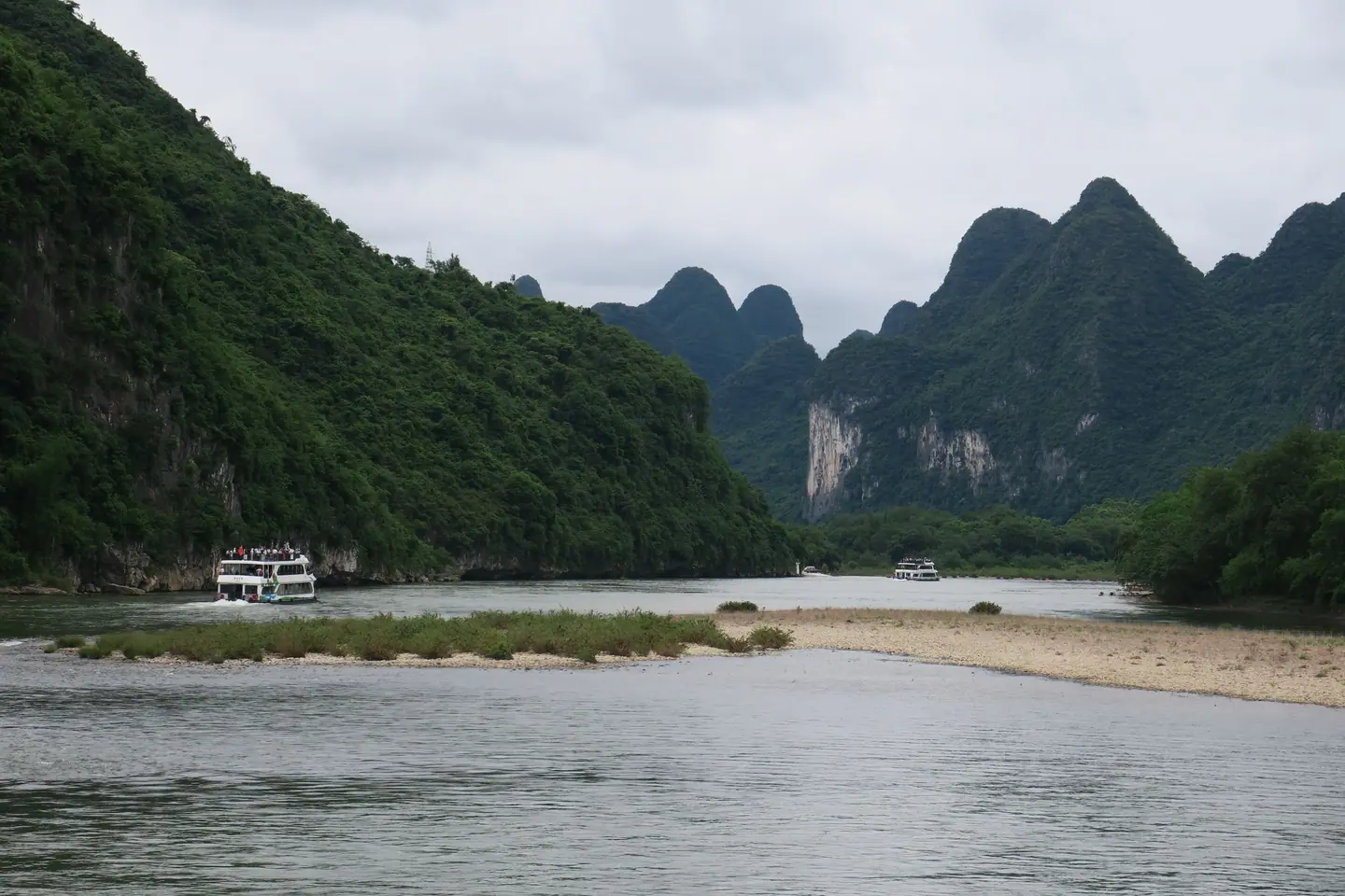 Barco de crucero navegando por el río Li entre montañas kársticas cubiertas de vegetación