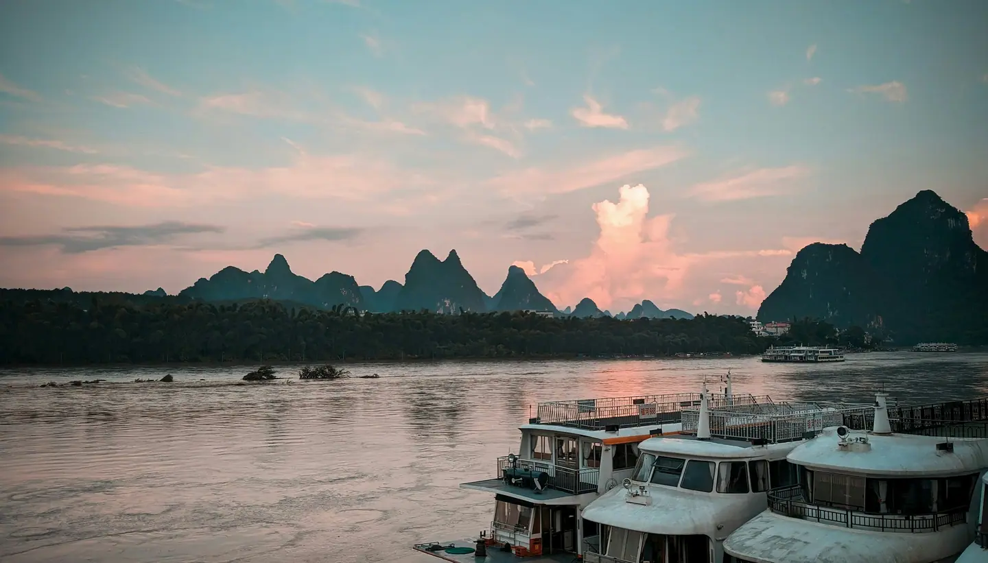 Barcos de crucero amarrados en el río Li al atardecer, con los picos kársticos de Guilin al fondo