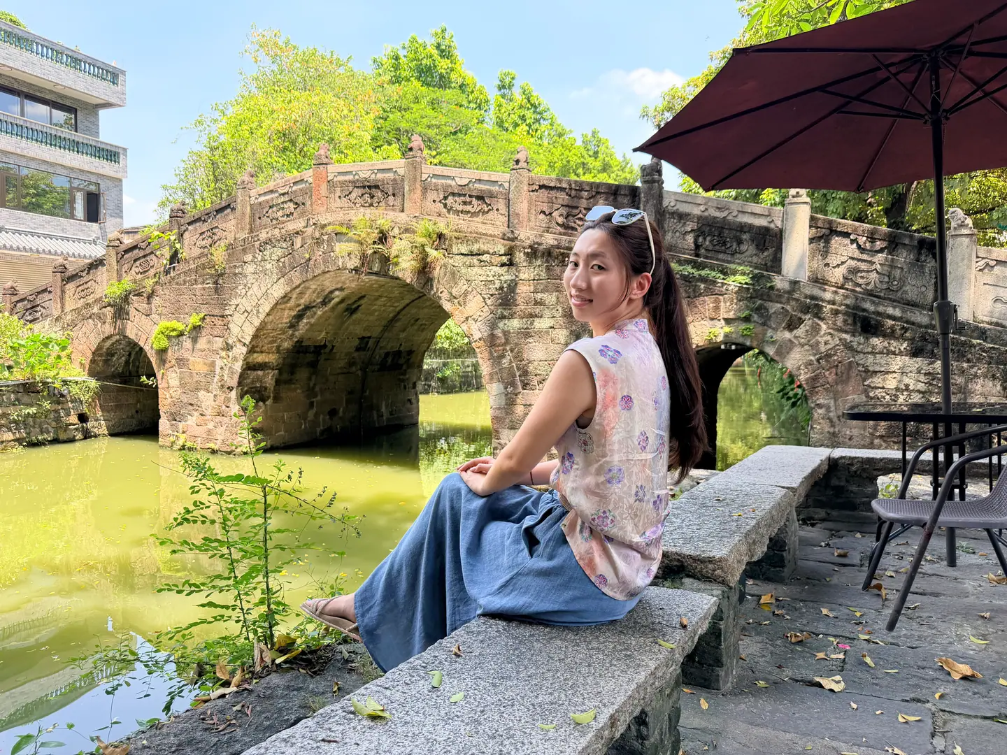 Viajera sentada junto a un antiguo puente de piedra en arco en Fengjian, Shunde