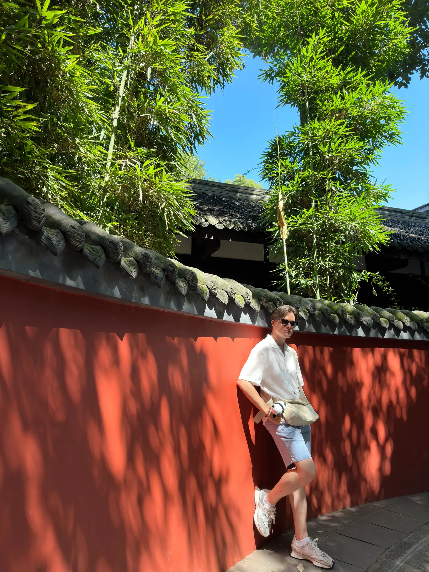 Viajero junto al célebre muro rojo con bambúes de la Cabaña de Paja de Du Fu, Chengdu