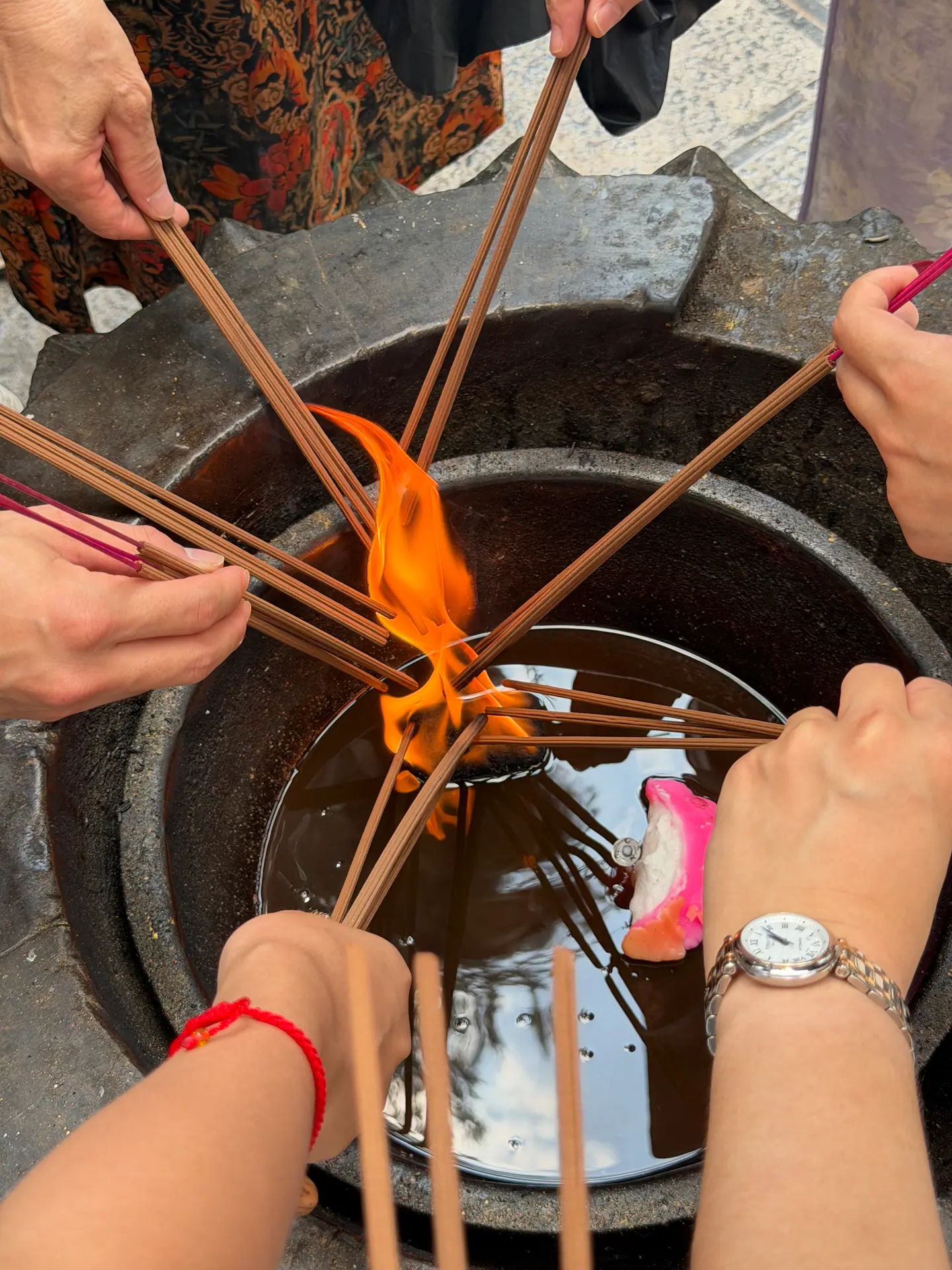 Manos encendiendo varillas de incienso en el fuego de un templo de Luoyang