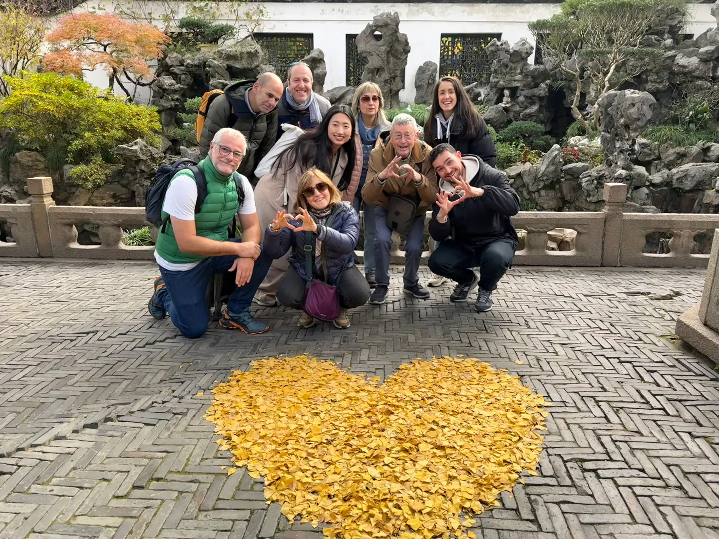 Grupo de viajeros de Hispasia junto a un corazón de hojas de ginkgo en el Jardín Yuyuan, Shanghái