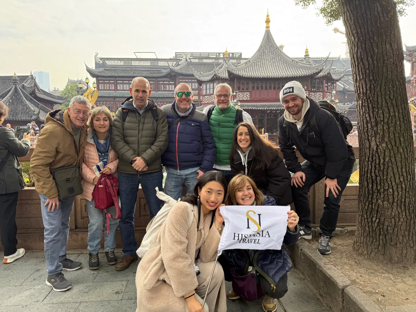 Grupo de viajeros de Hispasia Travel con su bandera junto al Jardín Yuyuan de Shanghái