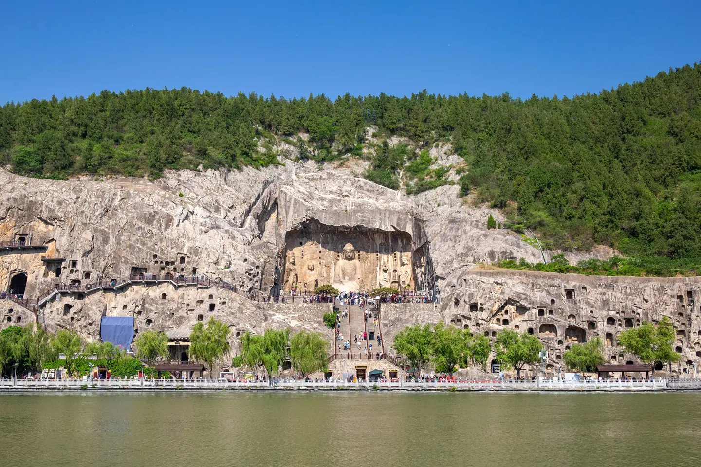 El acantilado de las Grutas de Longmen, con la gran cueva del Buda Vairocana, visto desde la otra orilla del río Yi bajo un cielo azul