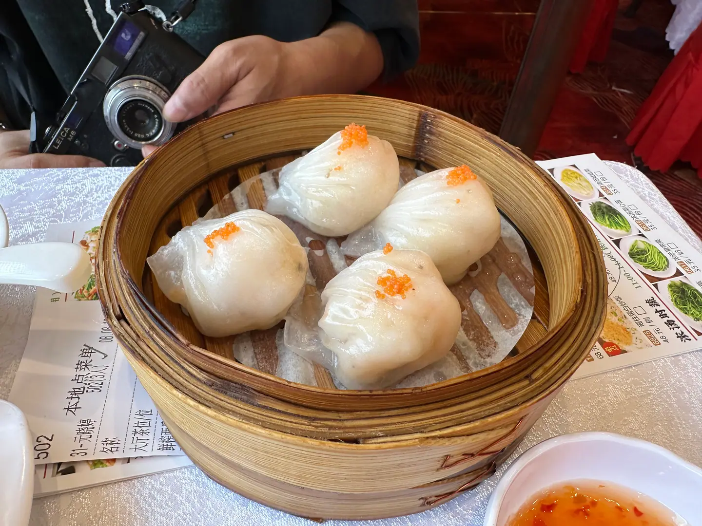 Cesta de bambú con empanadillas translúcidas de gamba (har gow) en un dim sum