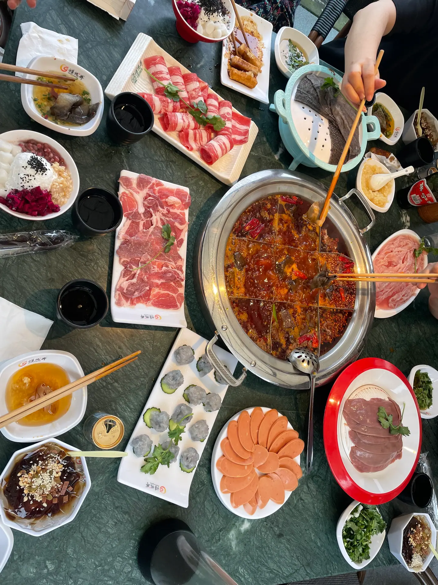 Mesa con olla caliente picante de Chongqing y platos de carne y verdura