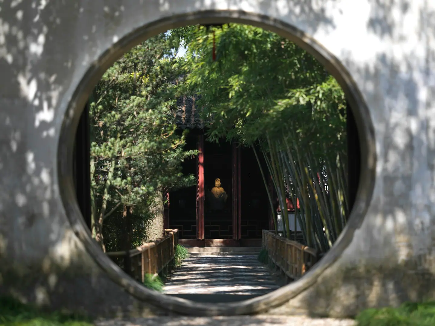 Puerta de luna que enmarca un camino entre bambúes en el jardín Liuyuan de Suzhou