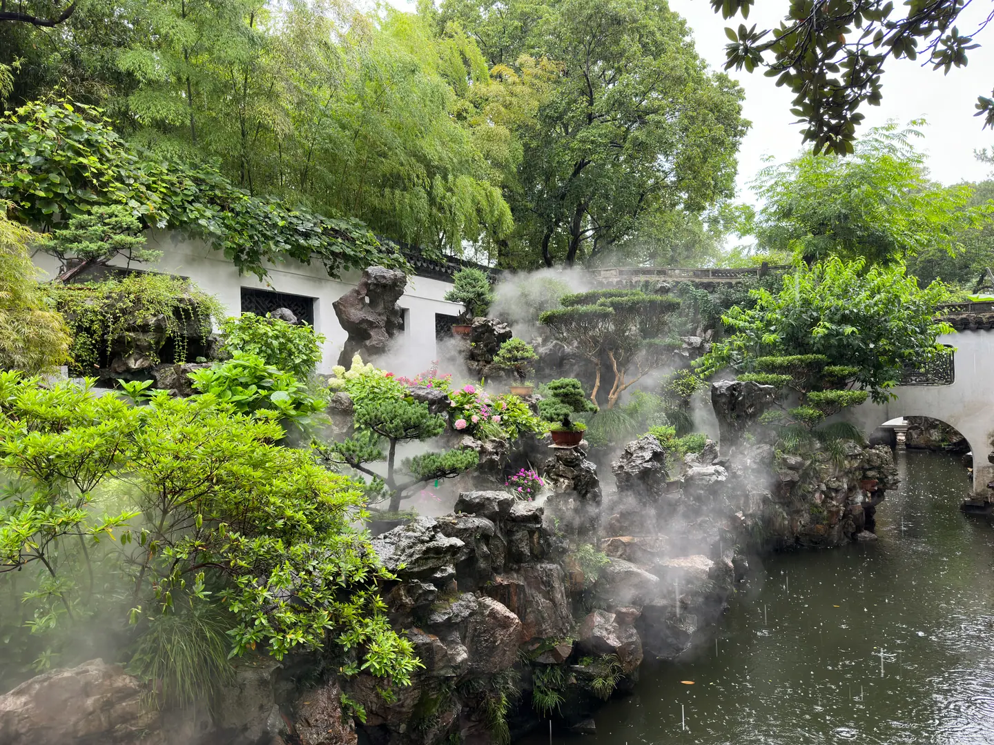 Jardín clásico con estanque brumoso, rocas y muros blancos ondulados en el Jardín Yuyuan, Shanghái