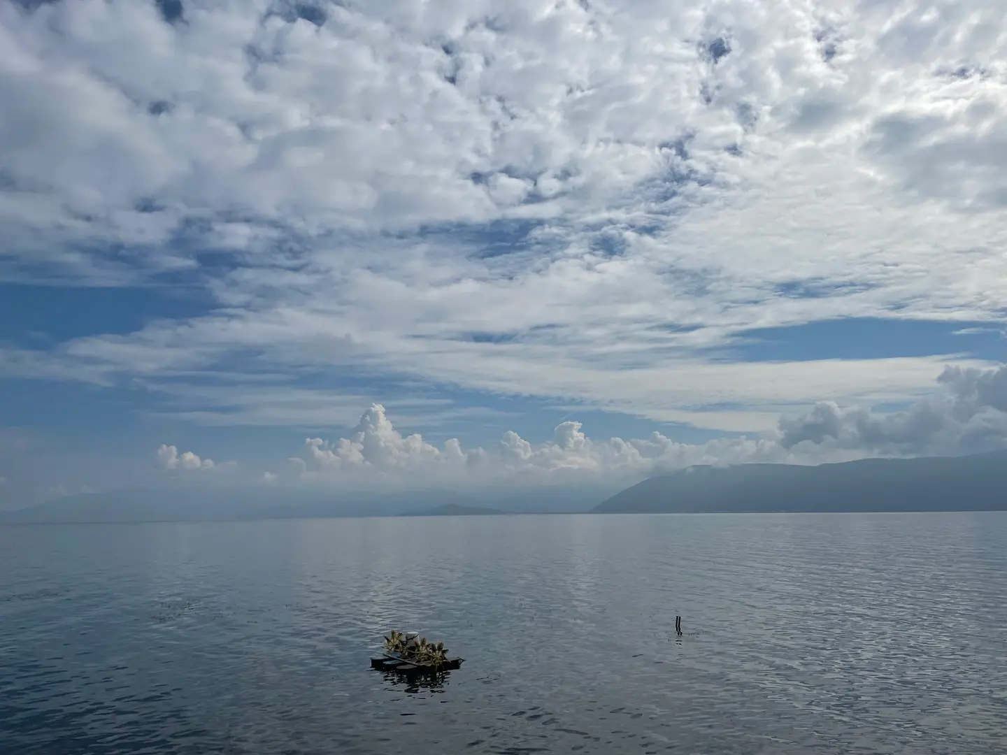 Aguas tranquilas del lago Erhai con las montañas al fondo y un cielo de nubes, Dali