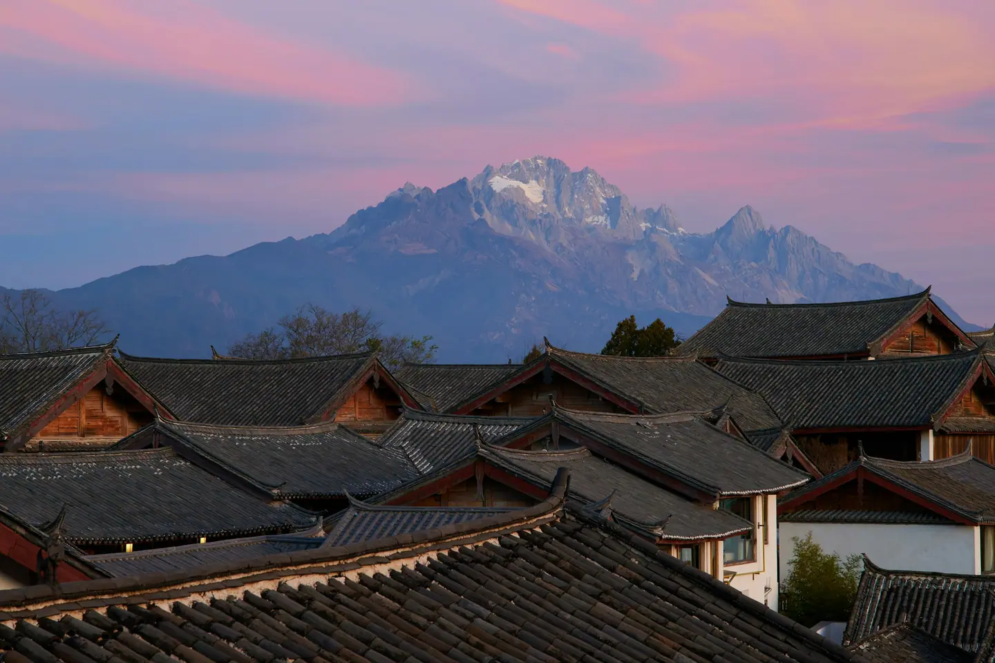 Tejados de la ciudad antigua de Lijiang al atardecer con la montaña nevada al fondo