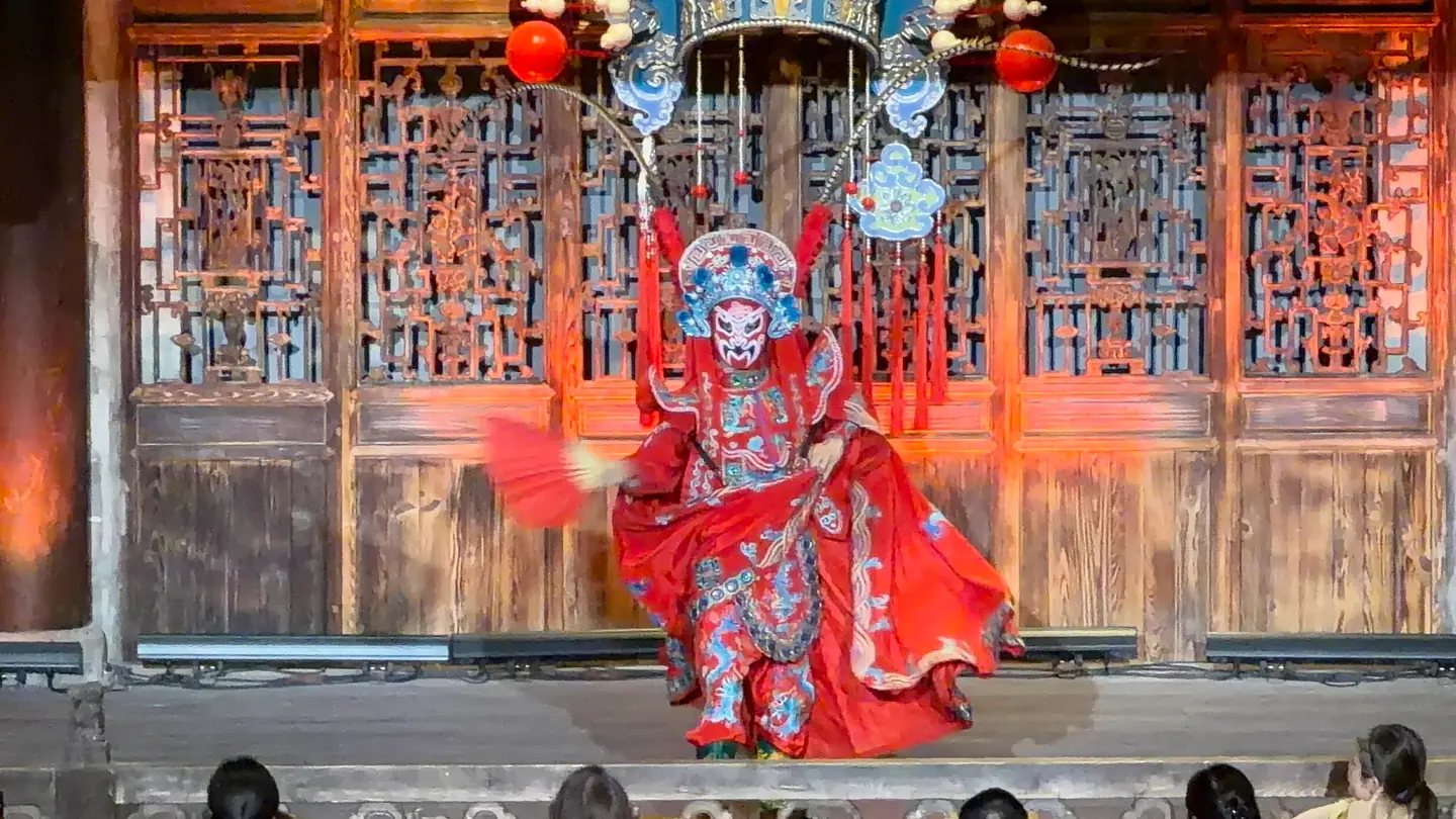 Actor de ópera de Sichuan con máscara y traje rojo durante el cambio de caras (bian lian)