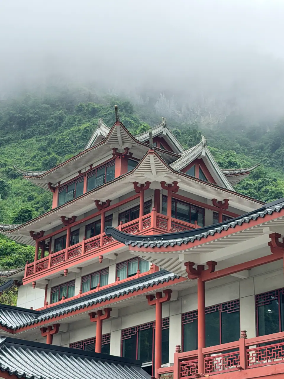 Edificio de varios tejados rojos con la montaña envuelta en niebla en Tianmen