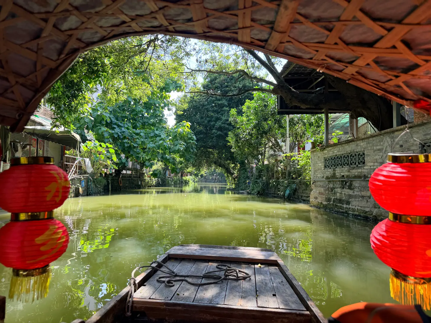 Vista desde una barca bajo un puente con farolillos rojos en el canal de Fengjian