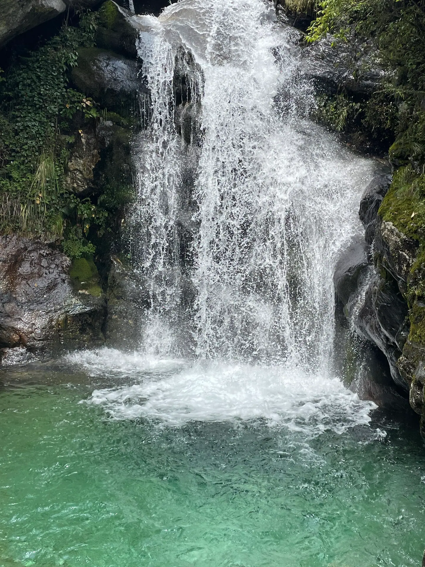 Cascada que se precipita en una poza de aguas turquesas en la montaña Cangshan, Dali