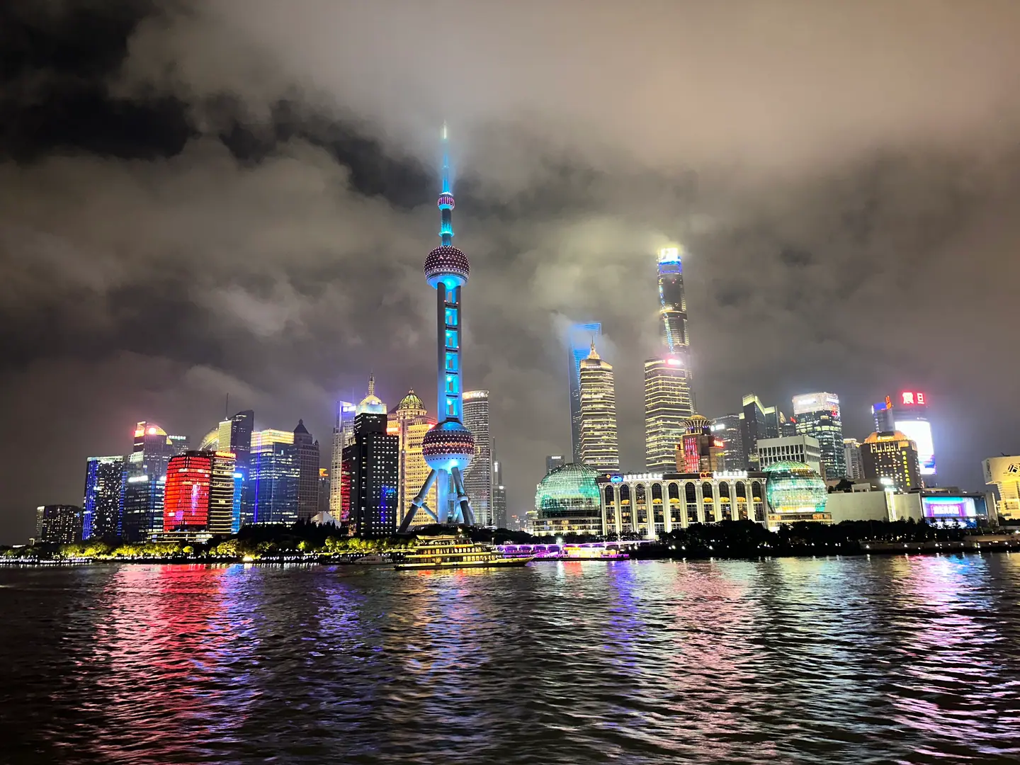 Rascacielos iluminados de Pudong y la Perla de Oriente reflejados en el río Huangpu