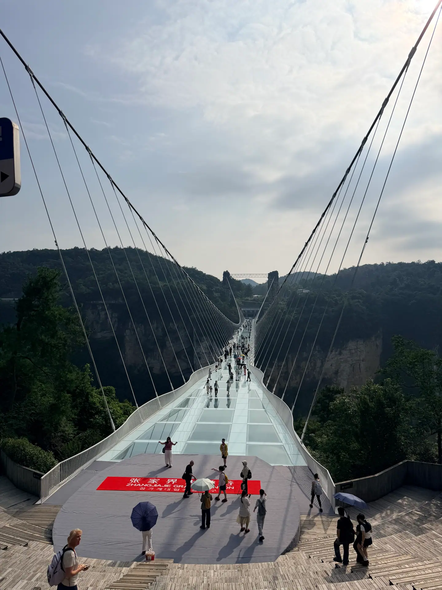 Visitantes sobre el puente de cristal del Gran Cañón de Zhangjiajie, suspendido sobre el valle