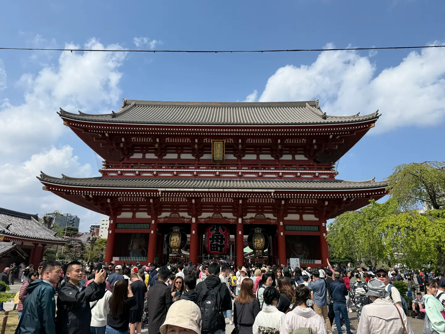 Puerta Hozomon de dos pisos del templo Senso-ji con visitantes en la explanada y cielo azul, Asakusa, Tokio