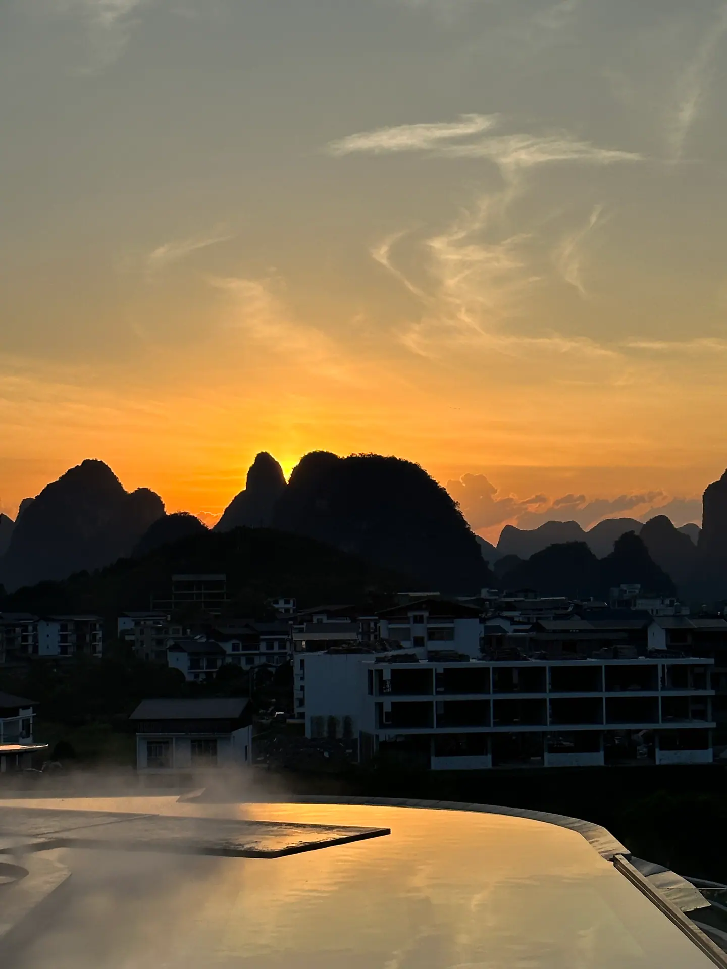 Sol poniéndose tras los picos kársticos de Yangshuo reflejado en una piscina