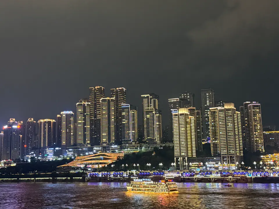Edificios iluminados y barcos en la orilla del río Jialing por la noche