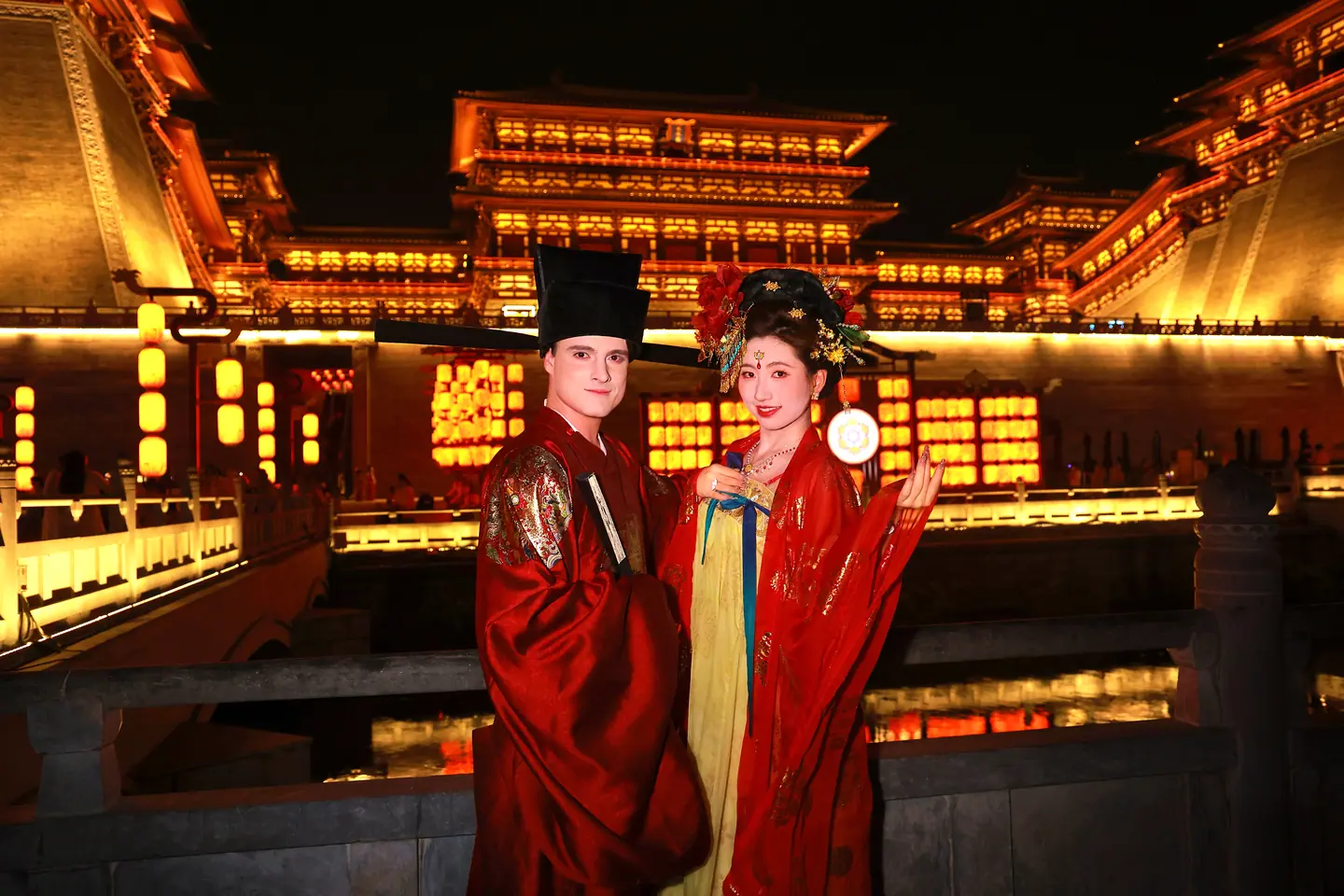 Pareja vestida con trajes de la dinastía Tang ante la puerta Yingtianmen iluminada de noche, Luoyang