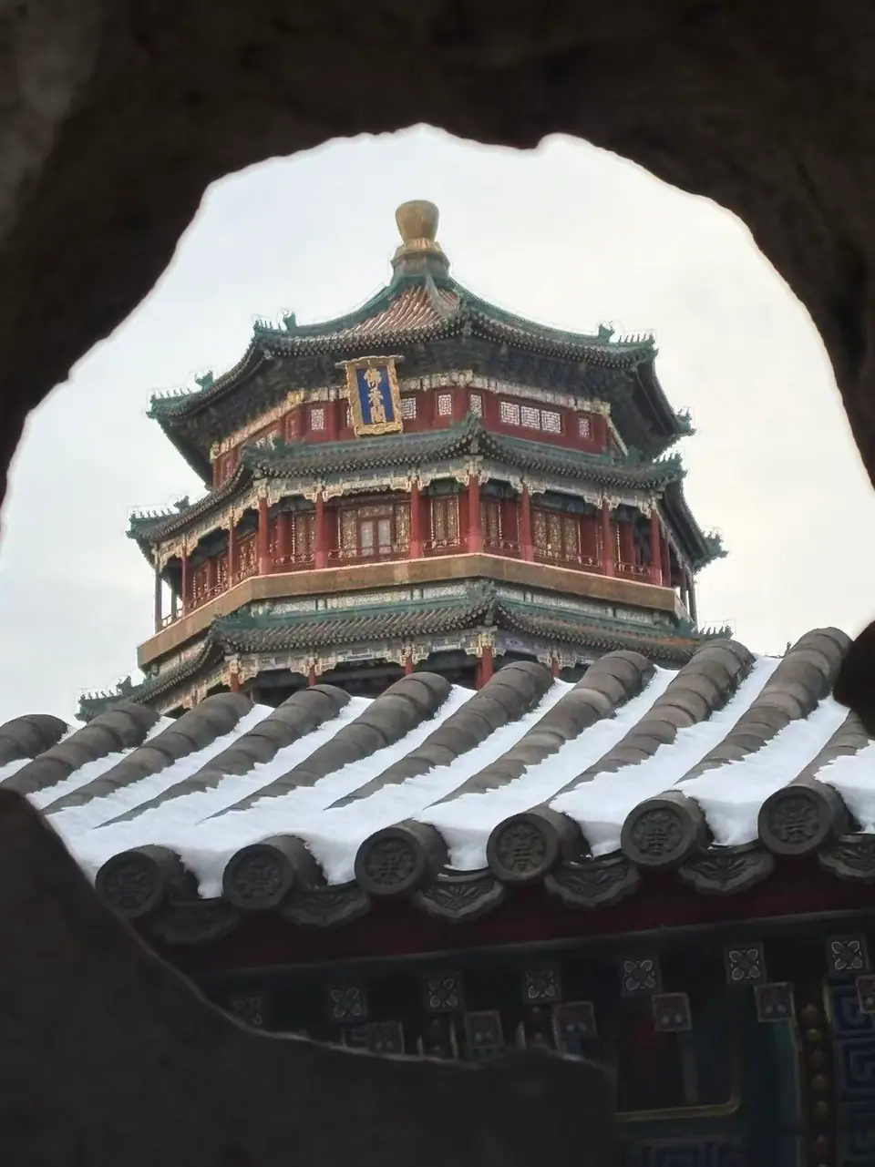 Torre del Incienso Budista del Palacio de Verano enmarcada por una ventana, con tejados nevados