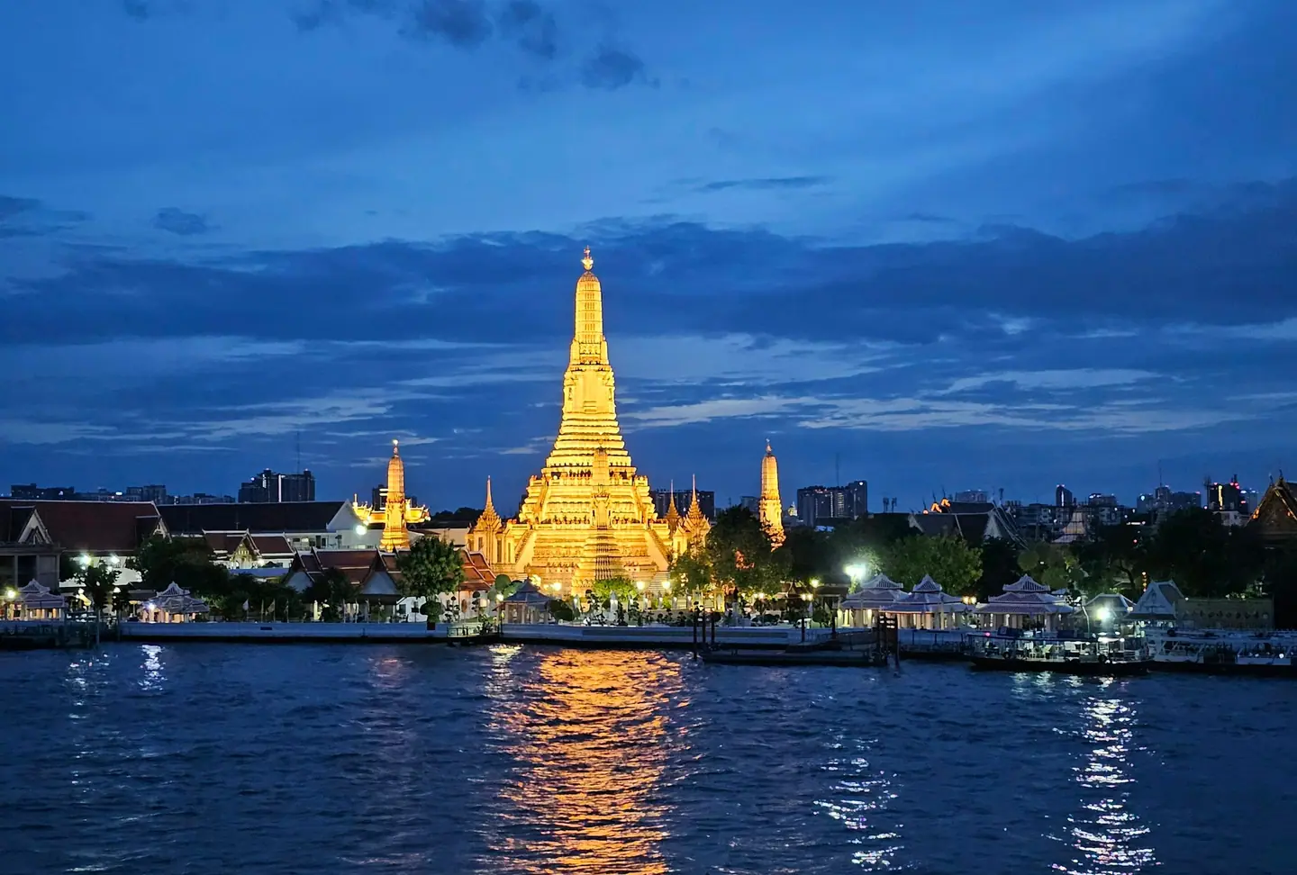 El templo Wat Arun iluminado al anochecer y reflejado en el río Chao Phraya, en Bangkok